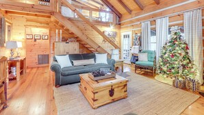 A cozy log cabin interior with a staircase, a living room with a sofa and coffee table, and a decorated Christmas tree. - Ridgetop Cabin in Blue Ridge! Wraparound Porch! (Blue Ridge)