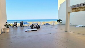 Un balcon avec vue sur la mer, une table, des chaises et des plantes en pot.