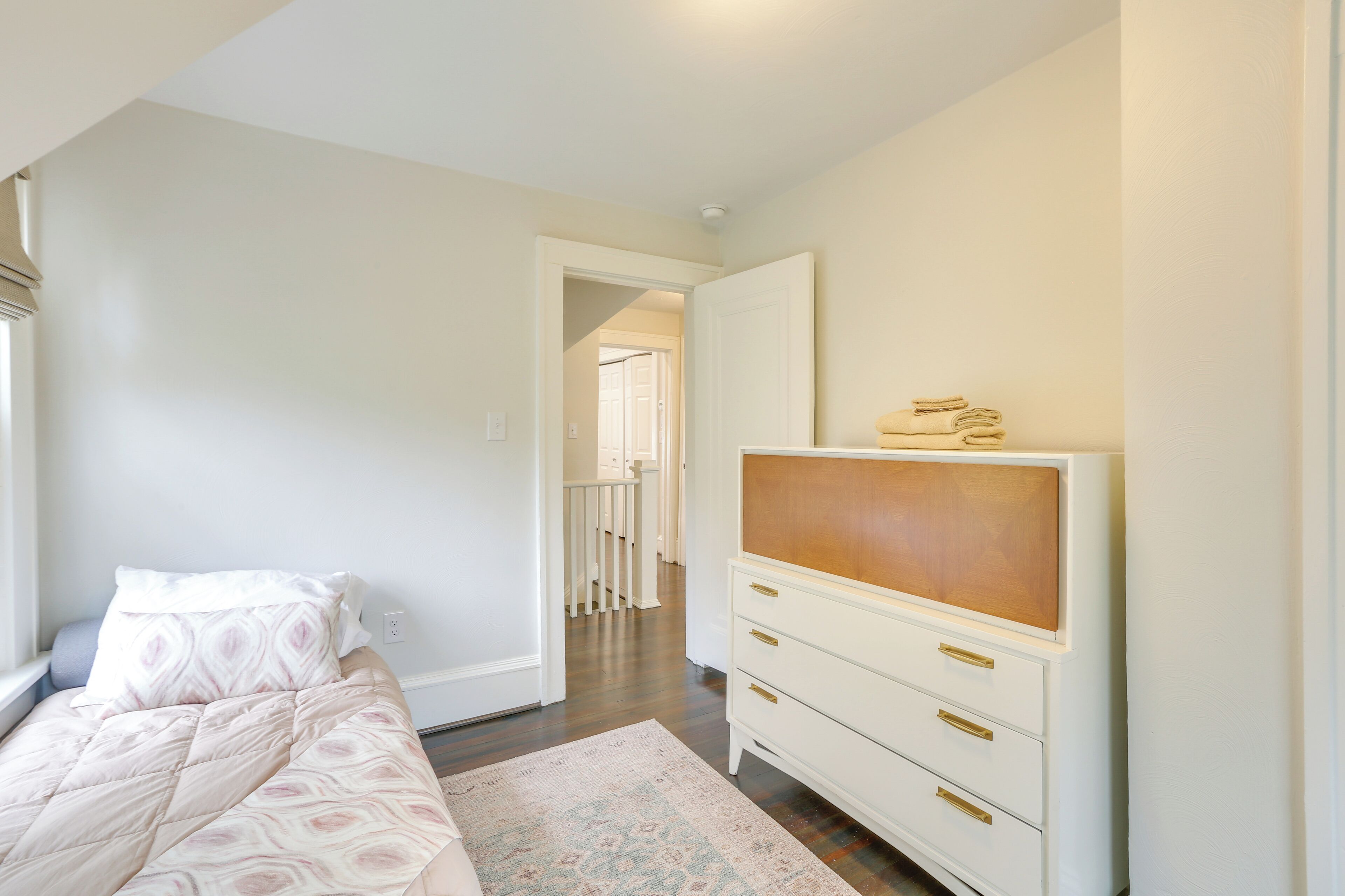 A bedroom with a bed, a dresser, and a walk-in closet.