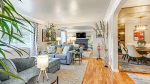 A modern living room with a sofa, coffee table, and a fireplace. There is a dining area with chairs and a table. - Pet Friendly: 2 Mi to Downtown Flushing (Flushing)