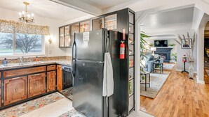 A kitchen with a black refrigerator, wooden cabinets, and a window with a view of trees. - Pet Friendly: 2 Mi to Downtown Flushing (Flushing)