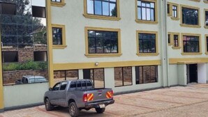 A building with multiple windows and a parked truck in front. - Furnished apartments in Migori : Deluxe Double Room (Migori)