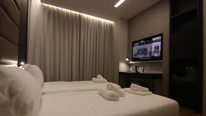 A hotel room with a large bed, a flat-screen TV mounted on the wall, and a curtain. - Boutique Hotel Adelar (Tirana)