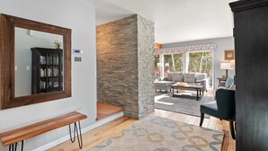 A living room with a wooden bench, a large mirror, a bookshelf, and a stone accent wall. - Hot Tub & Mountain Views: 5-Min to Frisco Main St. (Frisco)