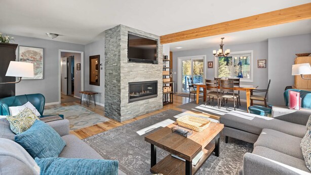 A modern living room with a stone fireplace, a dining area with a wooden table and chairs, and a view of the outdoors. - Hot Tub & Mountain Views: 5-Min to Frisco Main St. (Frisco)