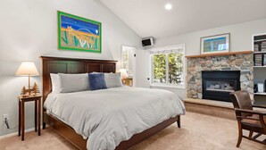 A bedroom with a large bed, a nightstand with a lamp, a stone fireplace, and a bookshelf. - Hot Tub & Mountain Views: 5-Min to Frisco Main St. (Frisco)