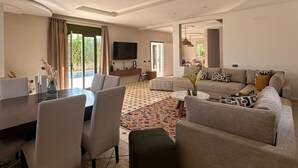 A spacious living room with a dining area, a sofa set, and a television.