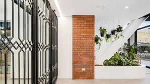 A modern interior with a geometric metal gate, a brick column, and hanging plants.