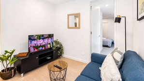 A modern living room with a flat-screen TV, a sofa, a coffee table, and a potted plant.