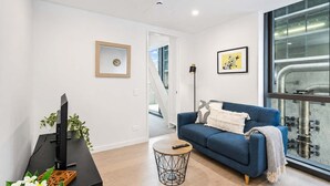 A modern living room with a blue sofa, a black TV stand, and a small round coffee table.