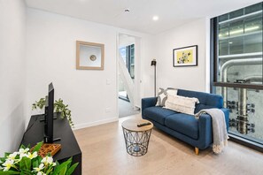 A modern living room with a blue sofa, a black TV stand, and a small round coffee table.