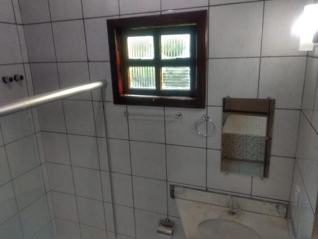 Ein gefliestes Badezimmer mit Fenster, Handlauf und Waschbecken.