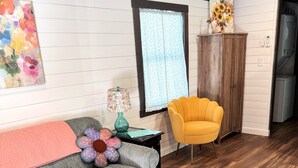 A cozy living room with a grey sofa, a yellow armchair, and a wooden cabinet. - Cozy 2 Bedroom Cottage in the Woods, Near Petoskey, Golf Courses and Ski Resorts (Petoskey)