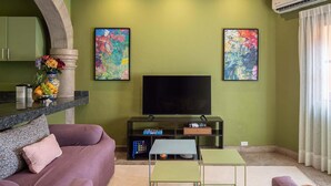 A living room with a TV, artwork, a sofa, a coffee table, and a stone pillar.