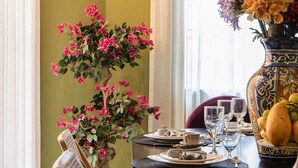 A dining table set with plates, glasses, and a vase of flowers.