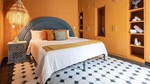 A bedroom with a bed, a nightstand, a wardrobe, and a hanging lamp.