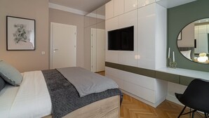 A modern bedroom with a bed, bedside table, TV, and a large mirror. - Holt Rossetti Residences Exclusive Urban Lofts (Bucharest)