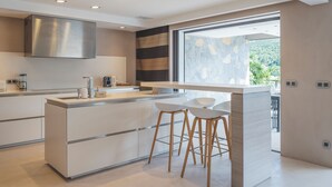 A modern kitchen with a large island, stainless steel appliances, and a view of greenery outside. - Beautiful 2-bedroom apartment in Gustavia with harbor view in Saint Barthélémy (Gustavia)