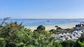 A coastal view with a beach, clear sky, and buildings with a uniform architectural style.