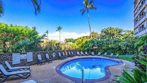 A pool area with lounge chairs and a stone wall. - Kamaole Beach Royale #312 3nd Flr, Ocean View, Steps from Beach, Full Kitchen (Kihei)