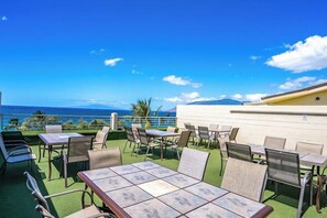 Une terrasse extérieure avec des tables et des chaises, offrant une vue panoramique sur l’océan.