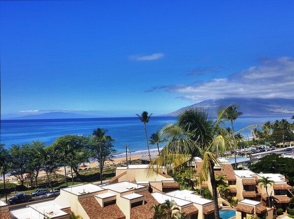 Un complejo turístico con varias cabañas, una piscina y vista a la playa.