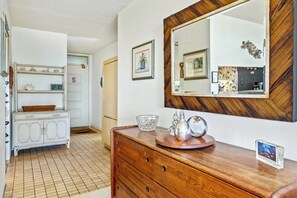 A hallway with a wooden dresser, a mirror, and a white cabinet.