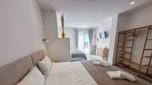 A hotel room with a large bed, a wooden wardrobe, a desk, and a chair. - La Tienda Nueva (Còmpeta)