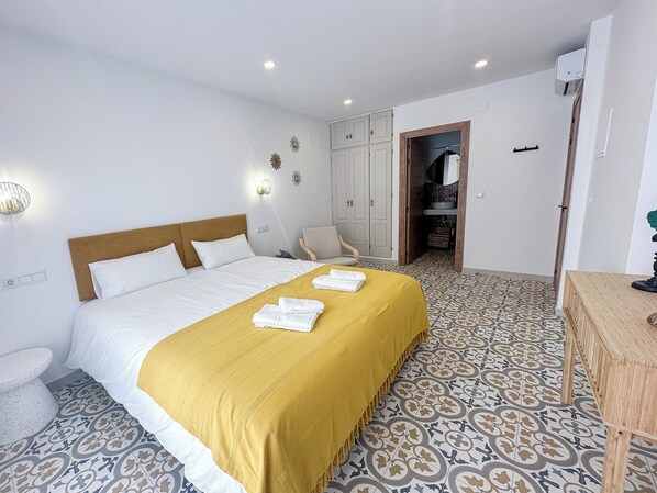 Ein Hotelzimmer mit Bett, Sessel, Schreibtisch und einem durchgegangenen Tür sichtbaren Badezimmer.