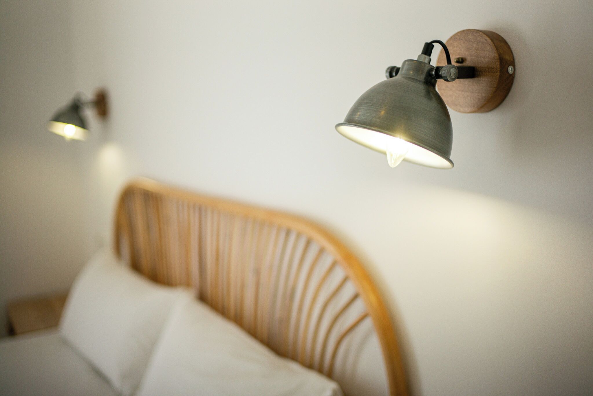Un lit avec une tête de lit en bois et deux lampes fixées au mur.