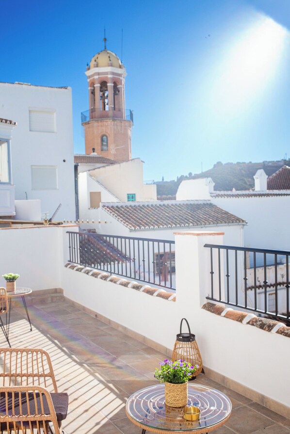 A rooftop terrace with a view of a tower, a table with a vase, and a railing. - La Tienda Nueva (Còmpeta)