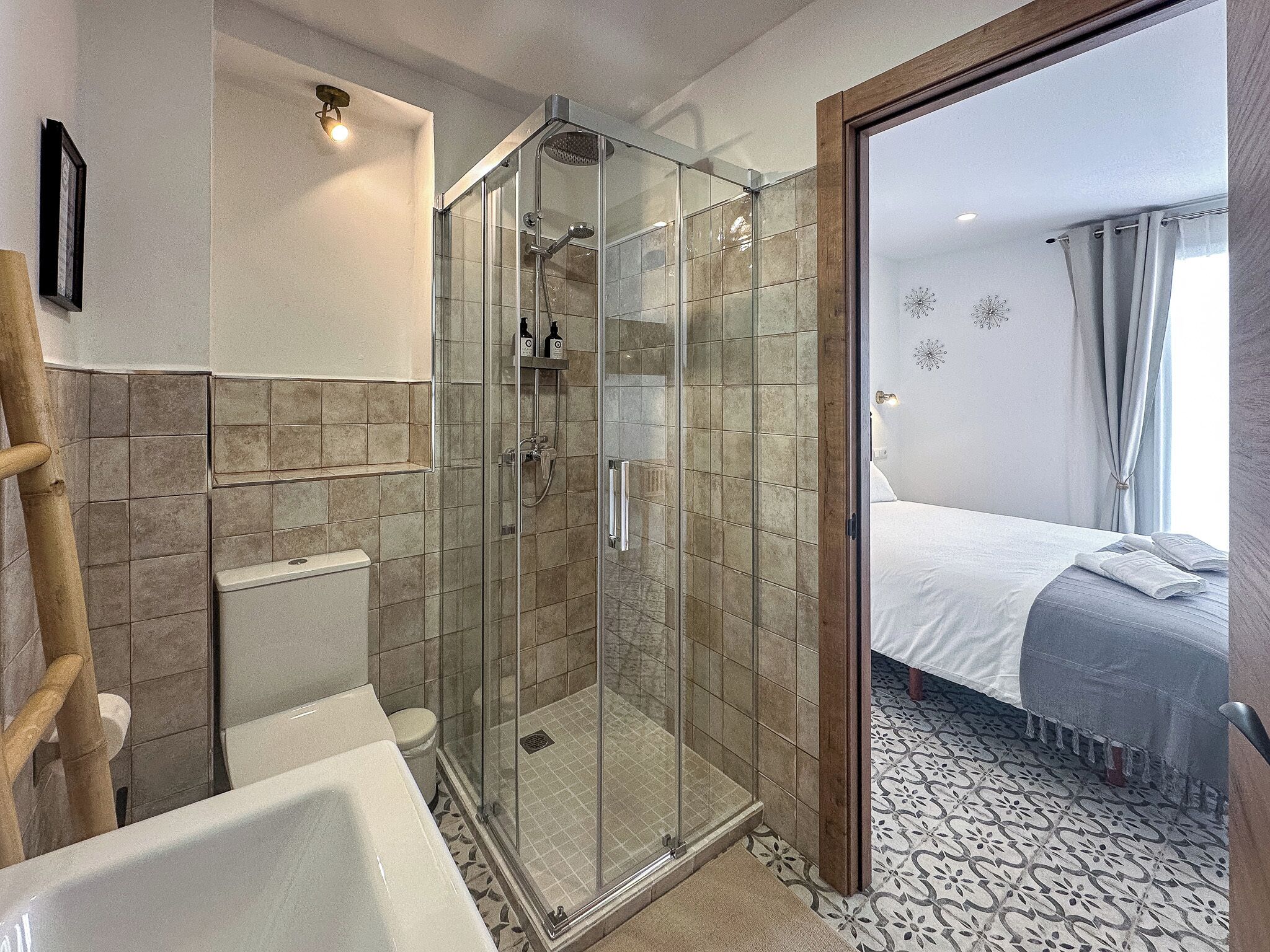 A bathroom with a glass-enclosed shower, a bathtub, and a toilet.