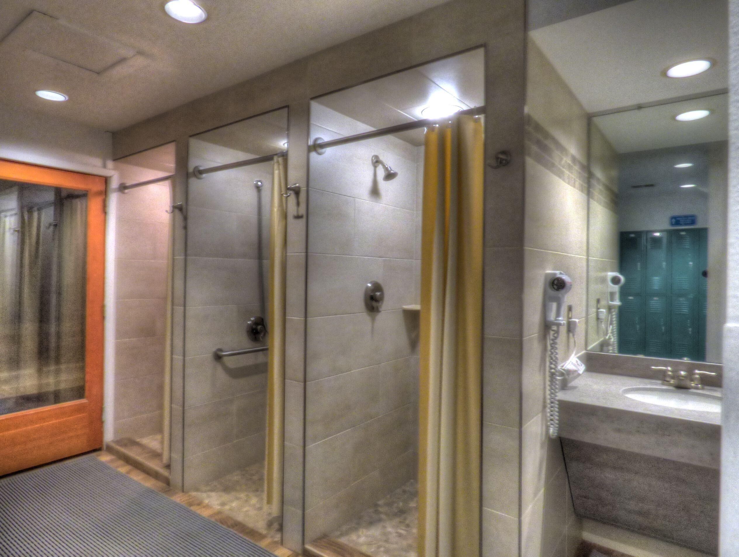 Un baño moderno con ducha de vidrio, tocador con espejo y lavamanos.