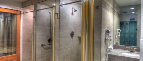 Un baño moderno con ducha de vidrio, tocador con espejo y lavamanos.