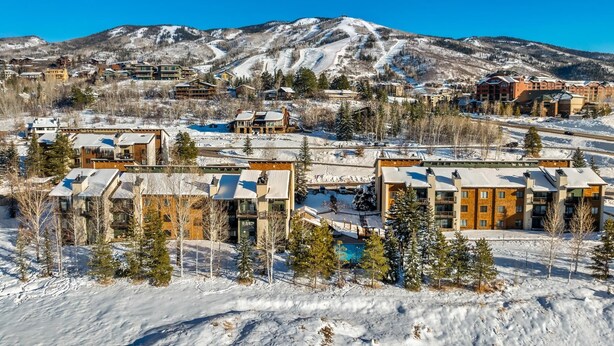A resort with multiple buildings, a pool, and a snowy mountain backdrop. - 2 Level Unit w/ Pool Hot Tubs Private Deck (Steamboat Springs)