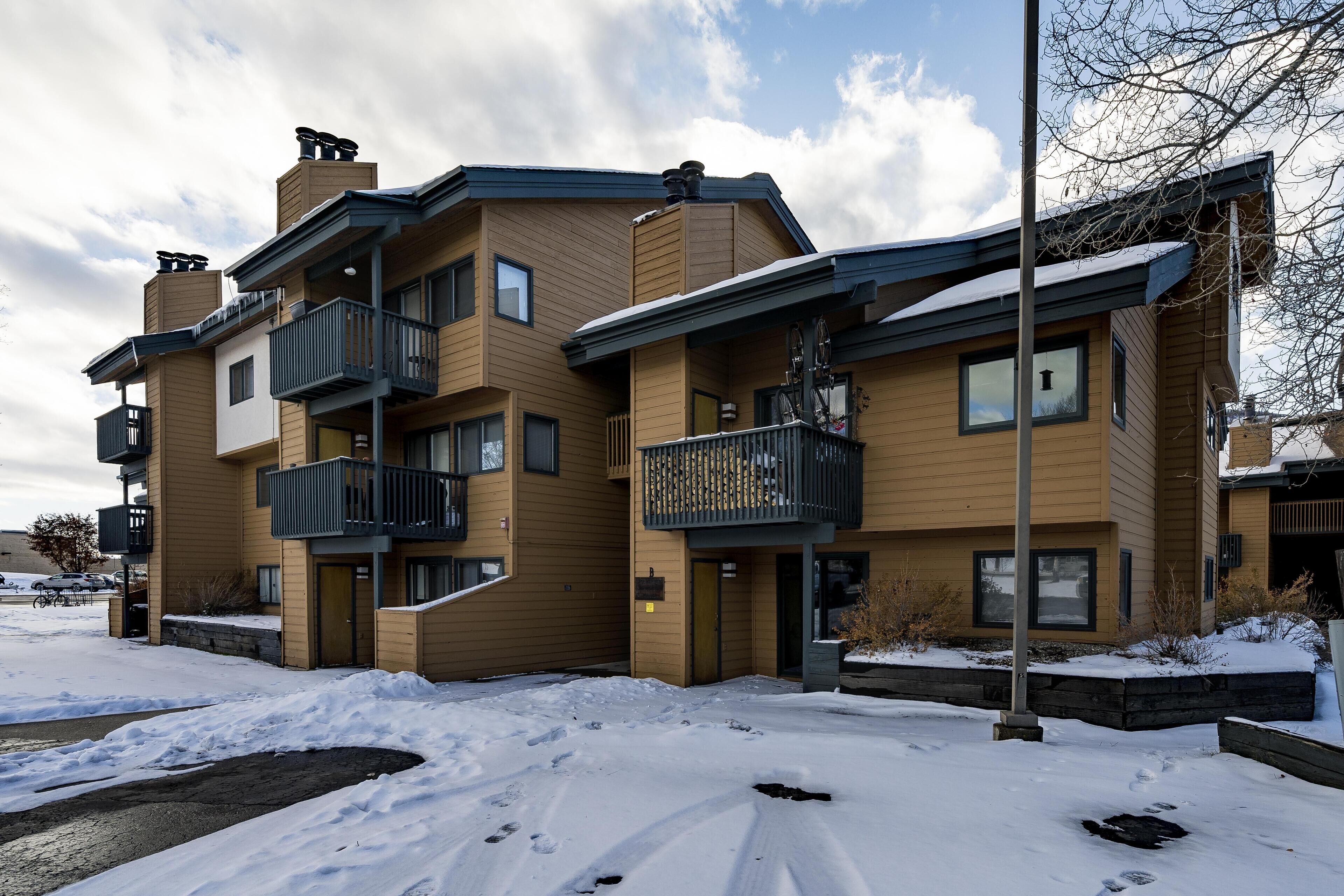 A multi-story residential building with balconies and a snow-covered ground.
