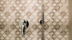 A bathroom with a hexagonal tile pattern and a chrome shower fixture. - DoppioSei -Guest House (Rome)