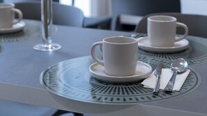 A dining table with white cups and saucers, a vase with flowers, and a flat-screen TV mounted on the wall. - DoppioSei -Guest House (Rome)