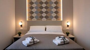 A hotel room with a large bed, two bedside tables with lamps, a decorative wall pattern, and two towels on the bed.