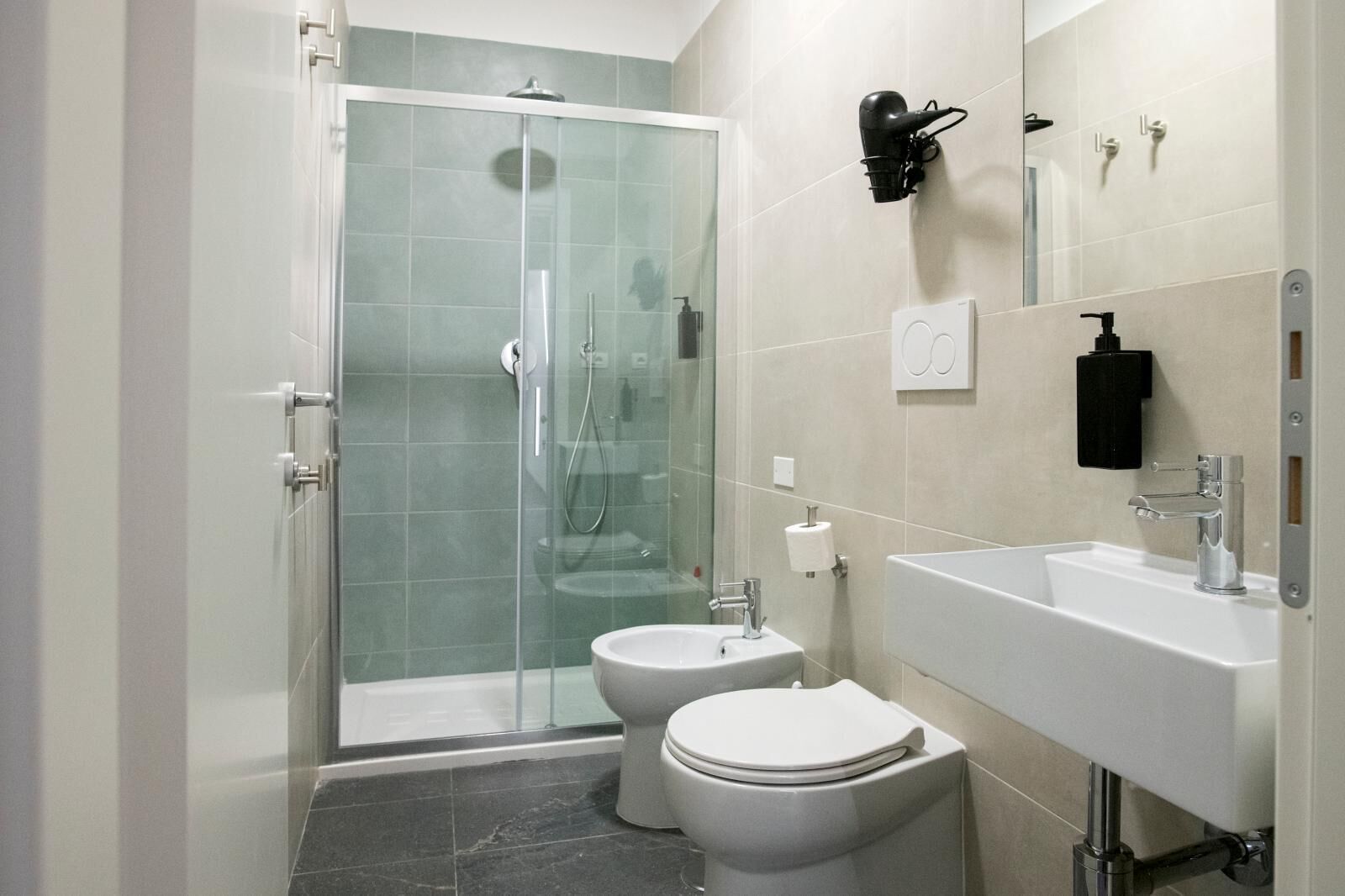 Ein modernes Badezimmer mit einer Duschkabine aus Glas, einem weißen Waschbecken und einer Toilette.