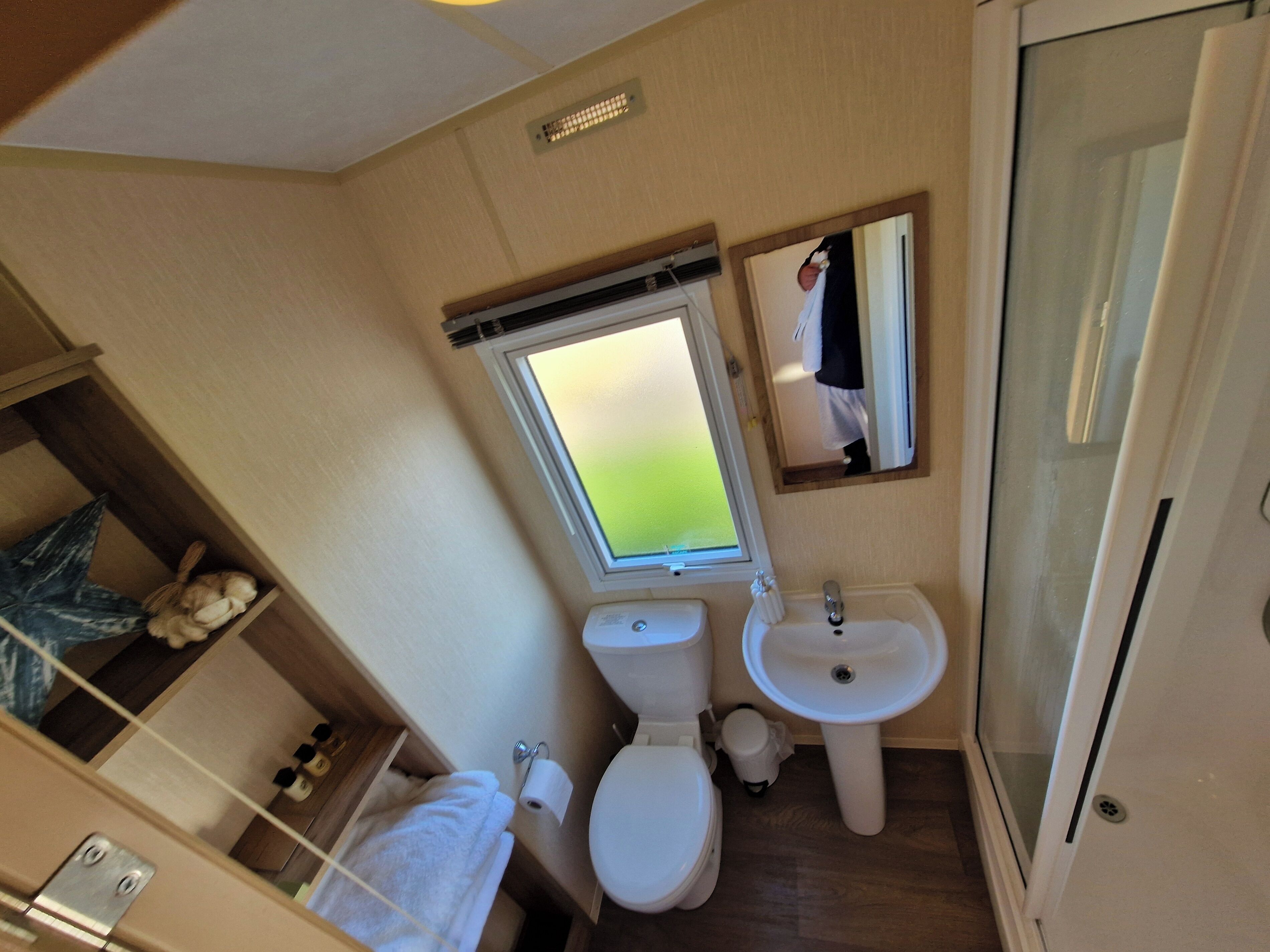 A compact bathroom with a toilet, sink, and a window.