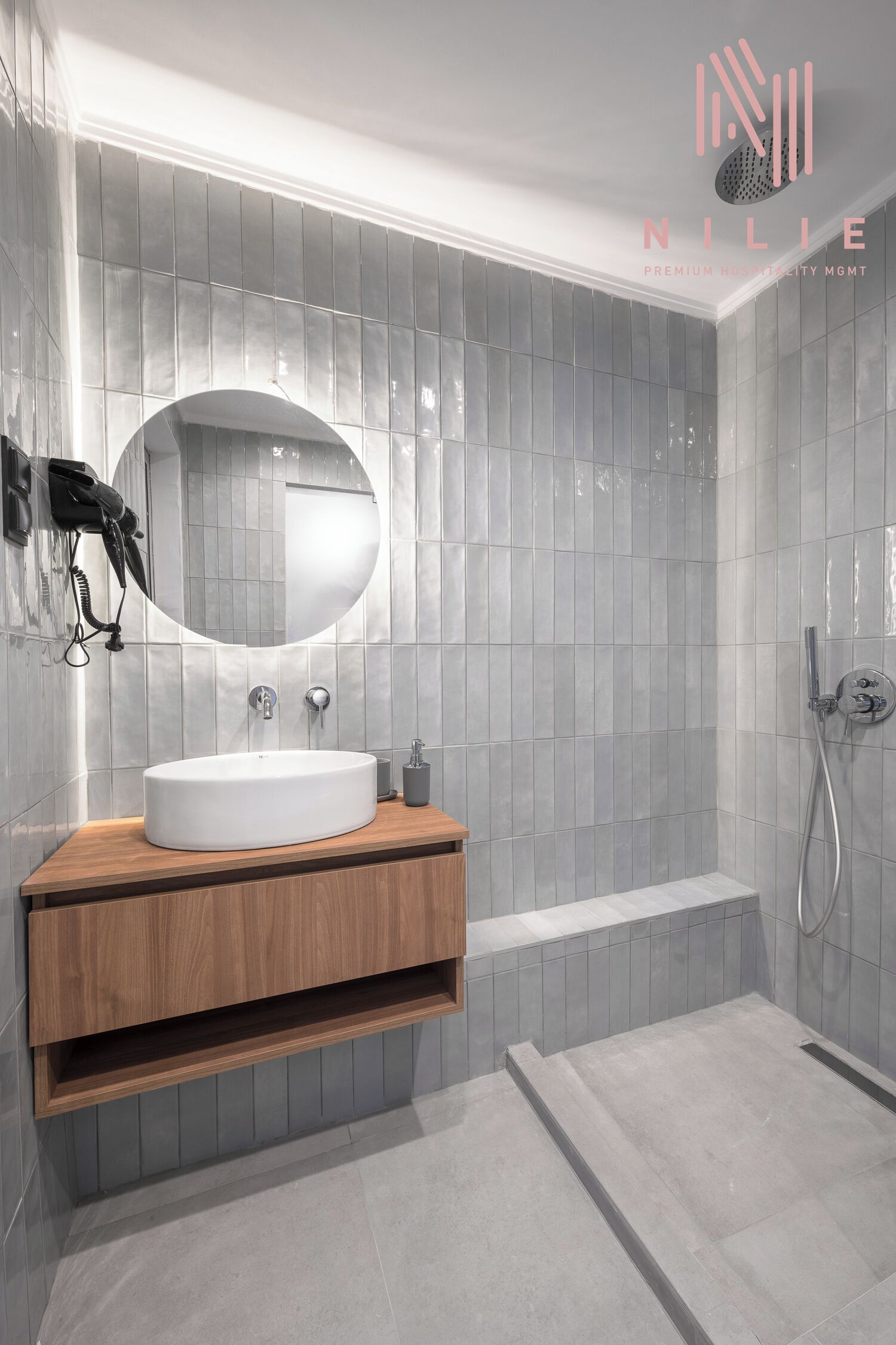 A modern bathroom with a round mirror, a wooden vanity, a bathtub, and a shower area.