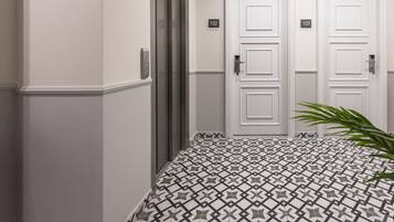 A hallway with two white doors, numbered 102 and 103, and a modern elevator.