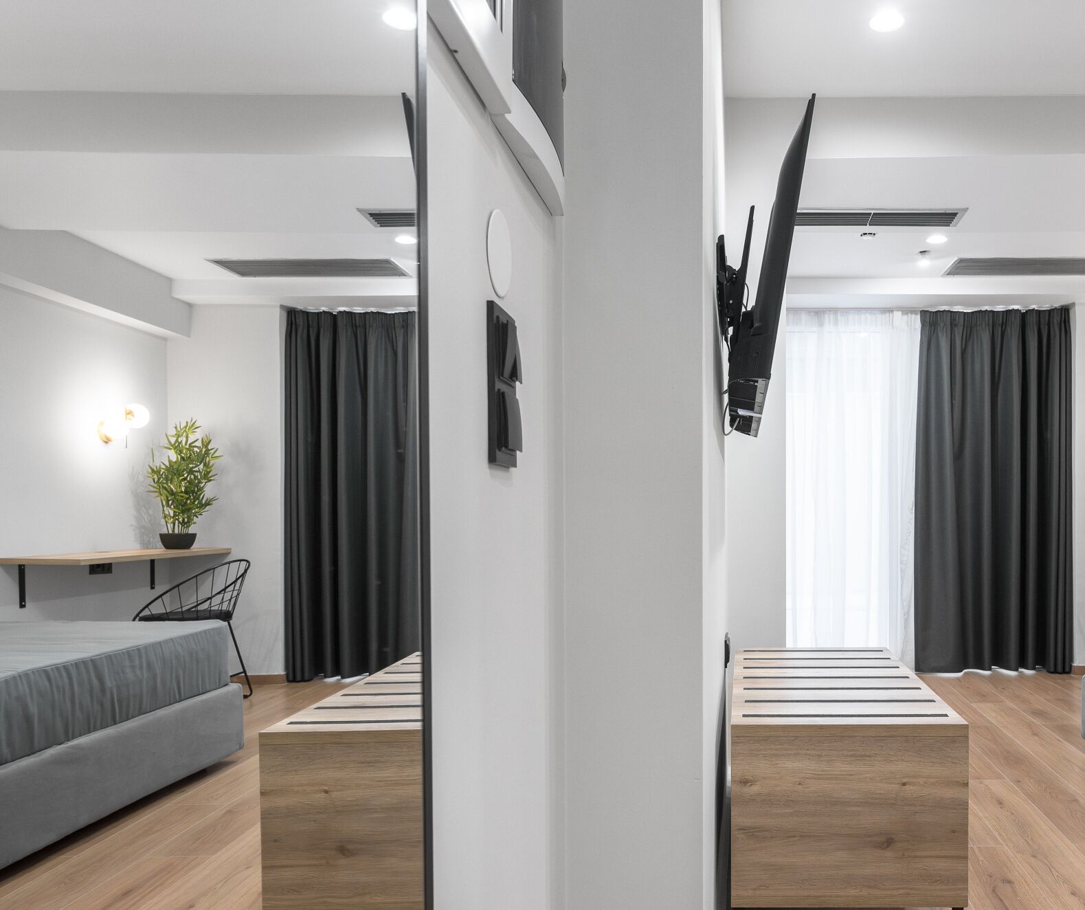 A modern, minimalist bedroom with a bed, bedside table, and a potted plant.