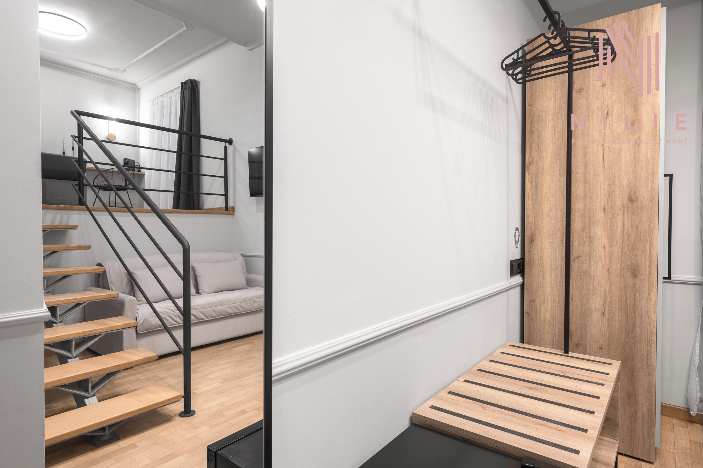A modern interior with a staircase, a sofa, and a wooden cabinet.