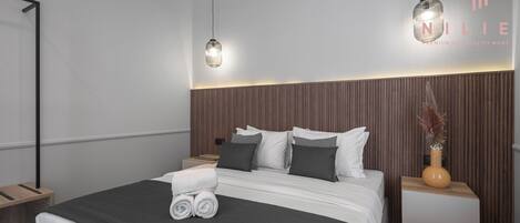A modern hotel room with a large bed, two bedside tables, and a nightstand.