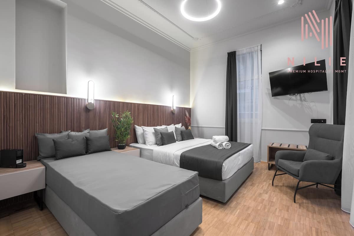 A modern hotel room with two beds, a flat-screen TV, a desk, and a chair.
