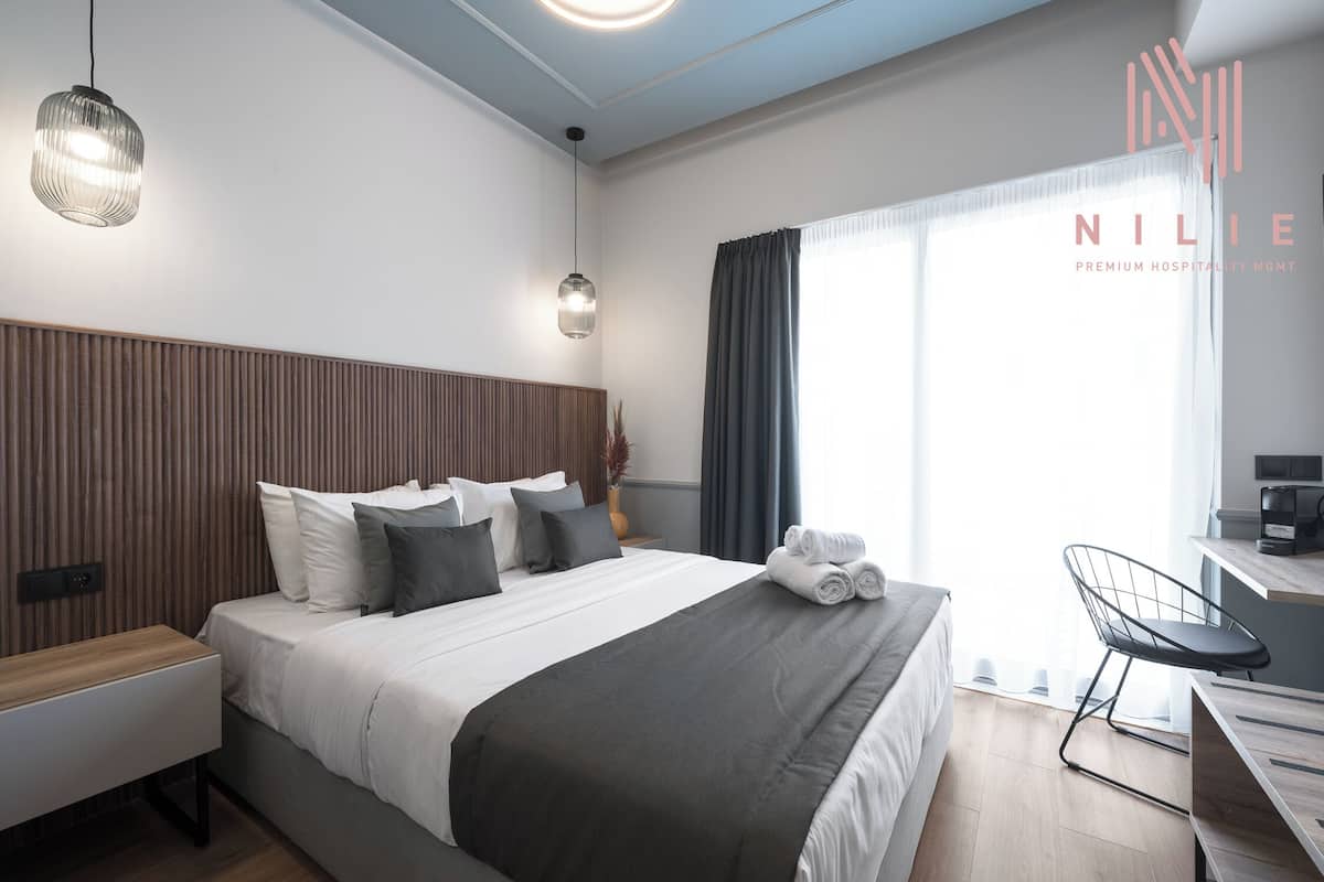 A modern hotel room with a large bed, bedside tables, a desk, and a chair.