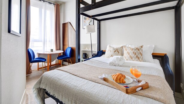 Habitación de hotel con cama, bandeja de desayuno y escritorio con sillas.