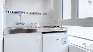 Cocina compacta con pileta integrada, un refrigerador pequeño y ventana que proporciona luz natural.